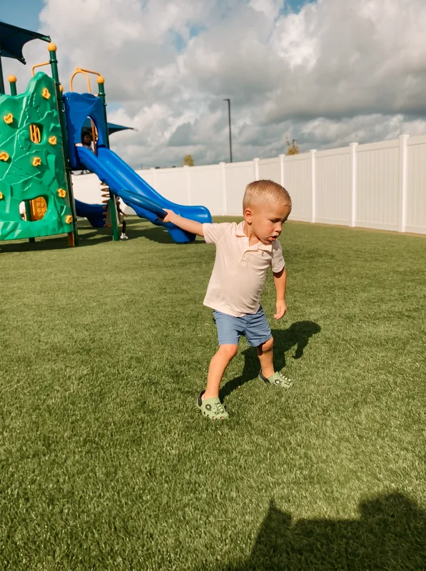 Child moving across an outdoor turf playground