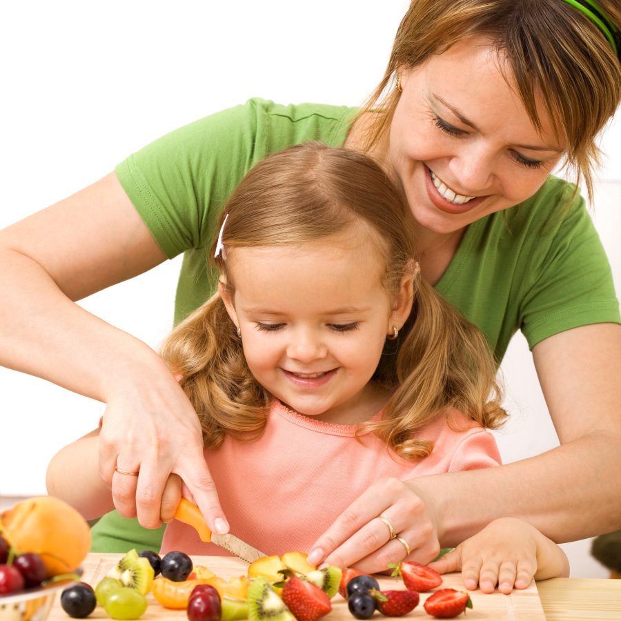 Woman and little girl preparing fruit salad